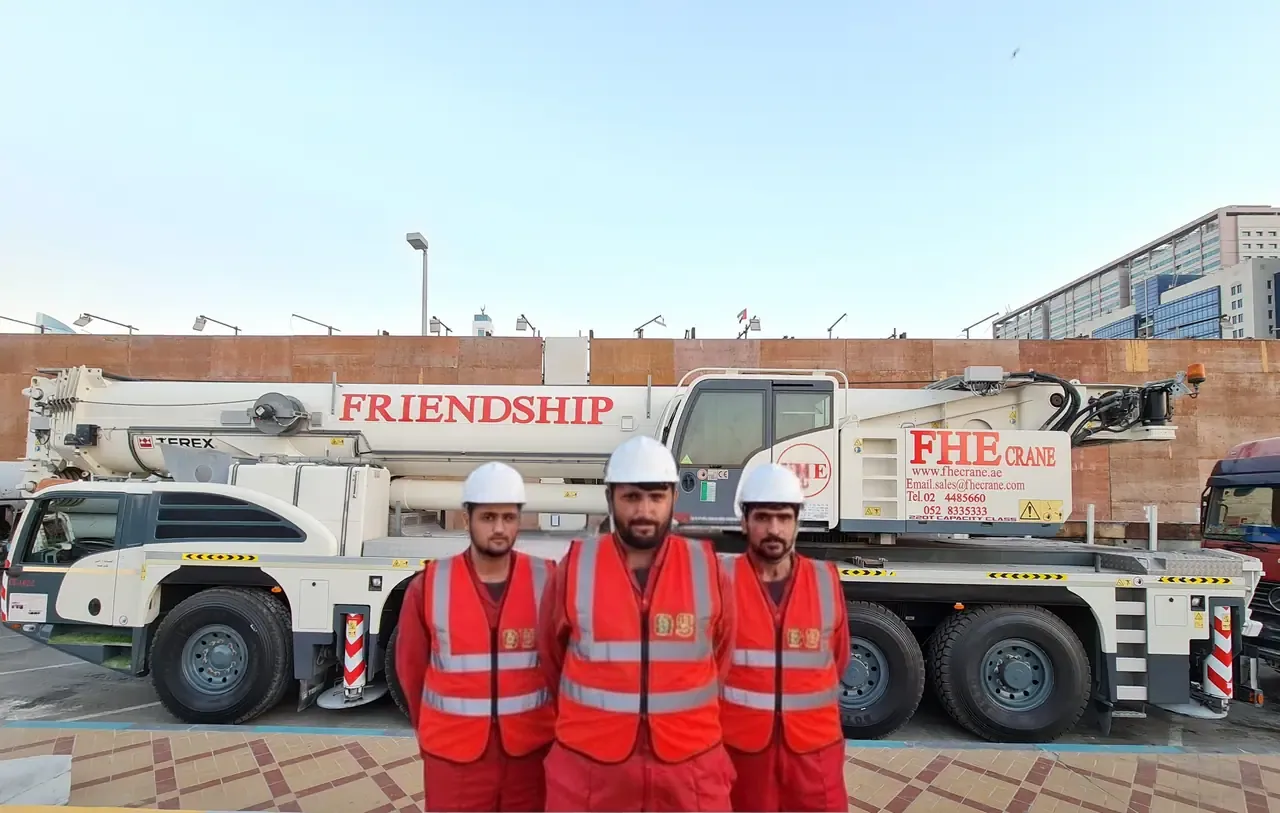 Three FHS crew in hard hats and hi-vis vests in front of a Terex FRIENDSHIP crane