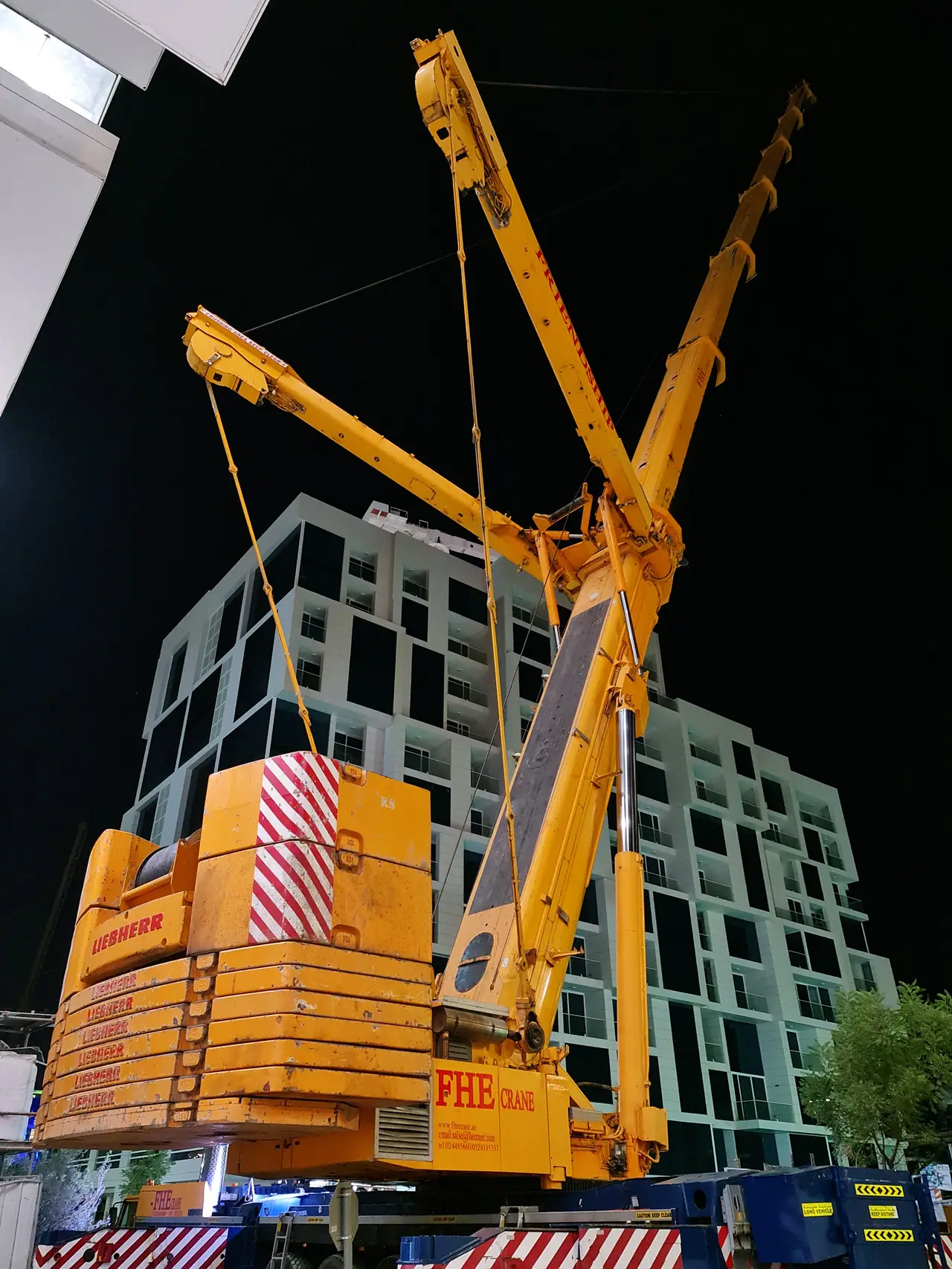 FHE heavy crane on a luffing jib beside a building at night