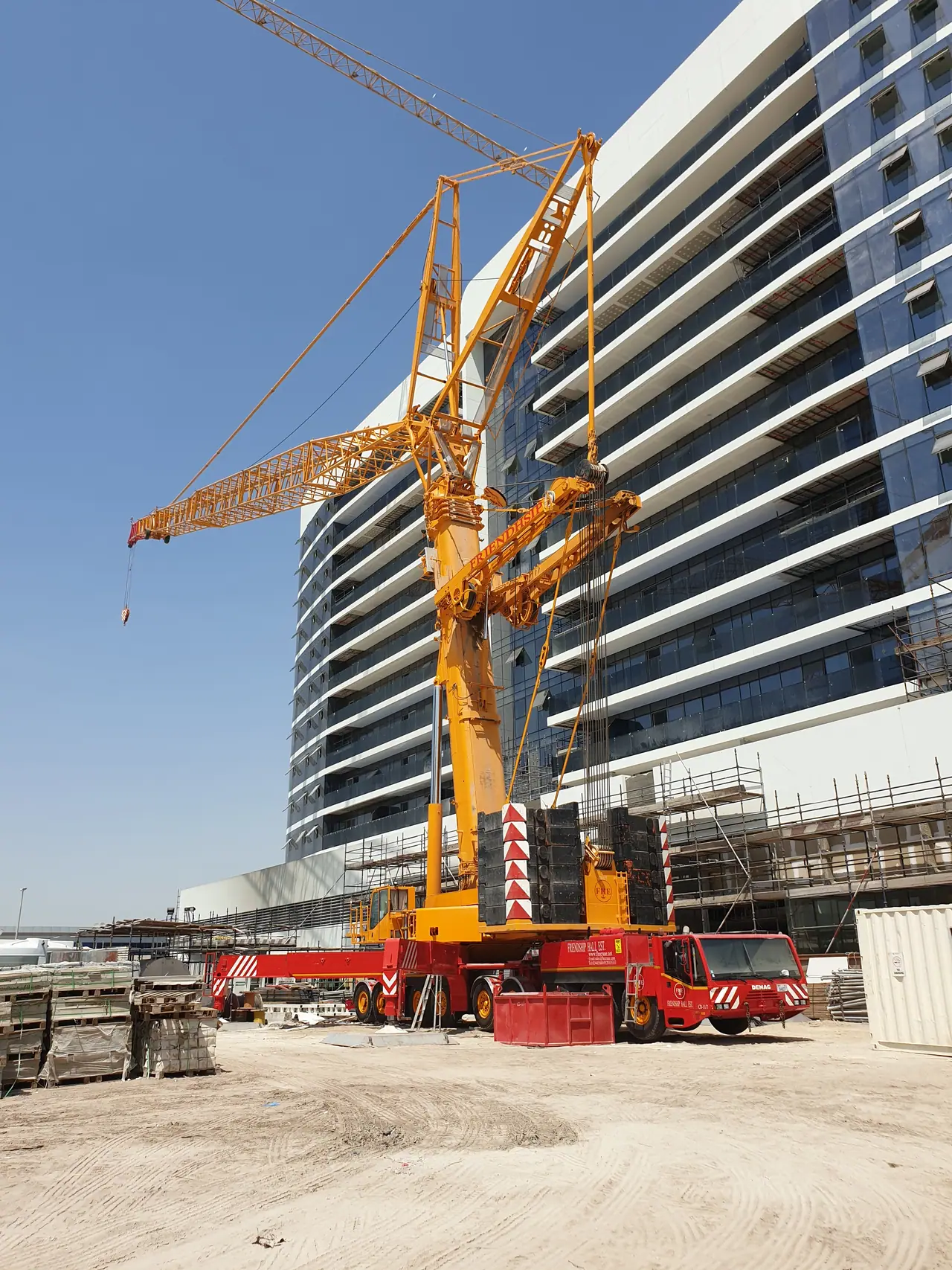 Yellow luffing crane alongside a curved mid-rise building