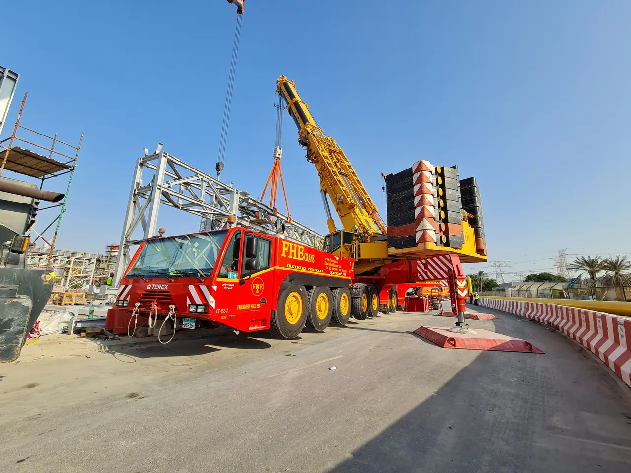 Red FHE Terex crane with a steel truss on the hook