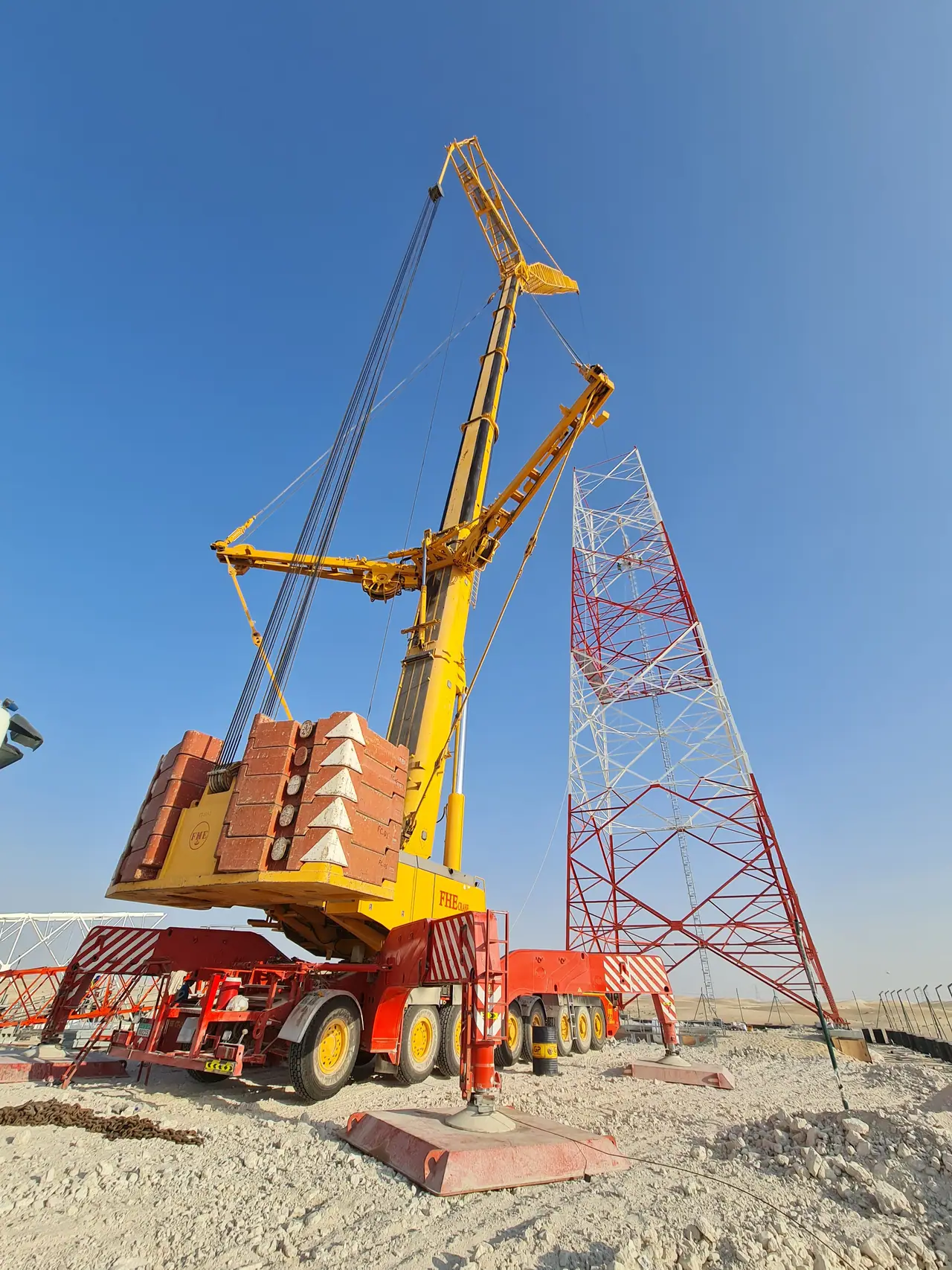 Heavy crane counterweight and luffing jib between lattice transmission towers